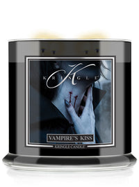 A black glass jar candle with a clear base, featuring a front label for 'Krinkle Candle' titled 'Vampire's Kiss'. The label shows a Halloween gothic illustration of a vampire's neck with a bite mark and a hand touching it.