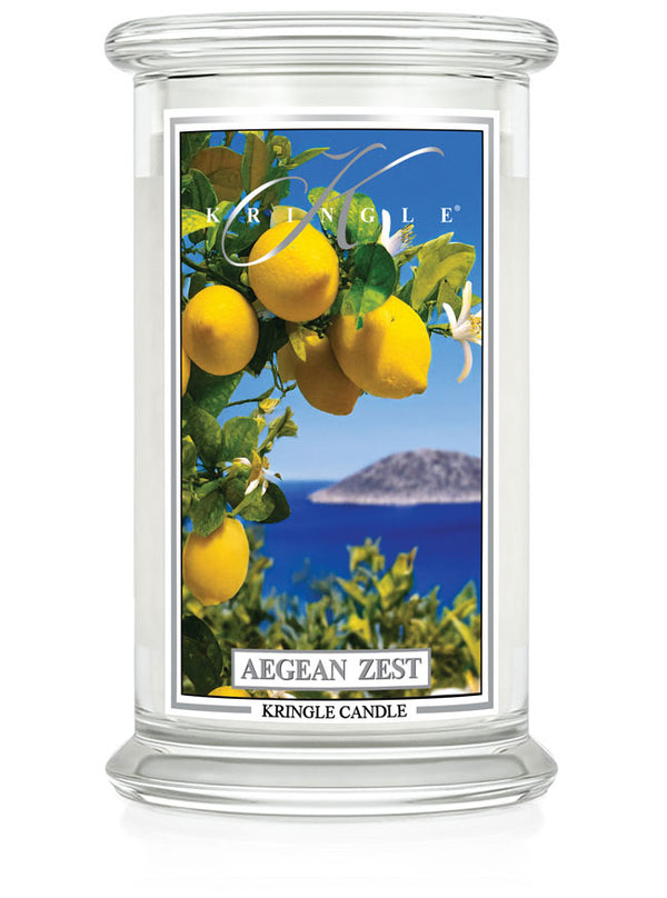 Kringle Candle Aegean Zest Large Jar Candle – A clear glass jar candle with a white wax interior, featuring a label with bright yellow lemons, green leaves, and white blossoms set against a deep blue ocean and an island in the background. The label includes the ‘Kringle Candle’ logo at the top, the fragrance name ‘Aegean Zest’ in bold, and ‘Kringle Candle’ branding at the bottom.