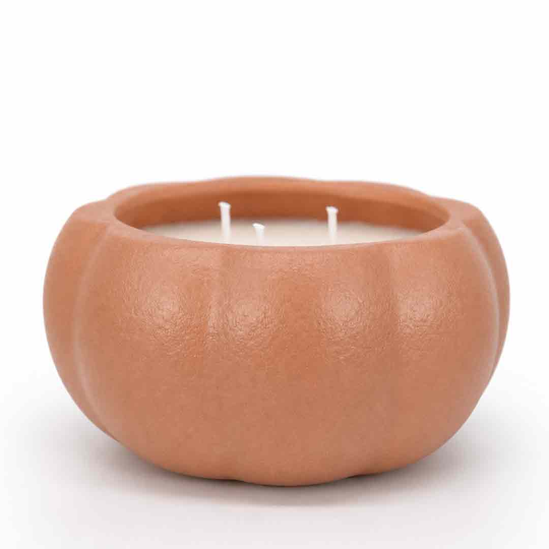 A two-wick candle in a sculpted, pumpkin-shaped terracotta container with a matte, textured finish, set against a plain white background.