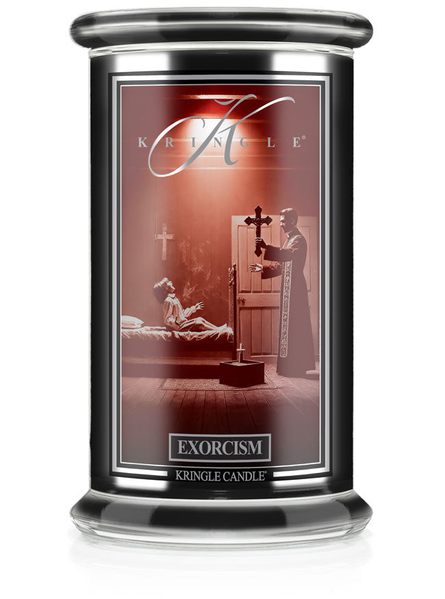 A Halloween candle jar with an unlit wick labeled "Exorcism." The label shows a scene of a priest performing an exorcism.