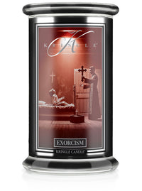 A Halloween candle jar with an unlit wick labeled "Exorcism." The label shows a scene of a priest performing an exorcism.