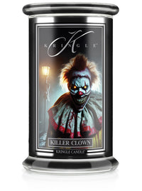 A lit Halloween candle in a glass jar with a "Killer Clown" label featuring a sinister clown and a glowing streetlamp in the…
