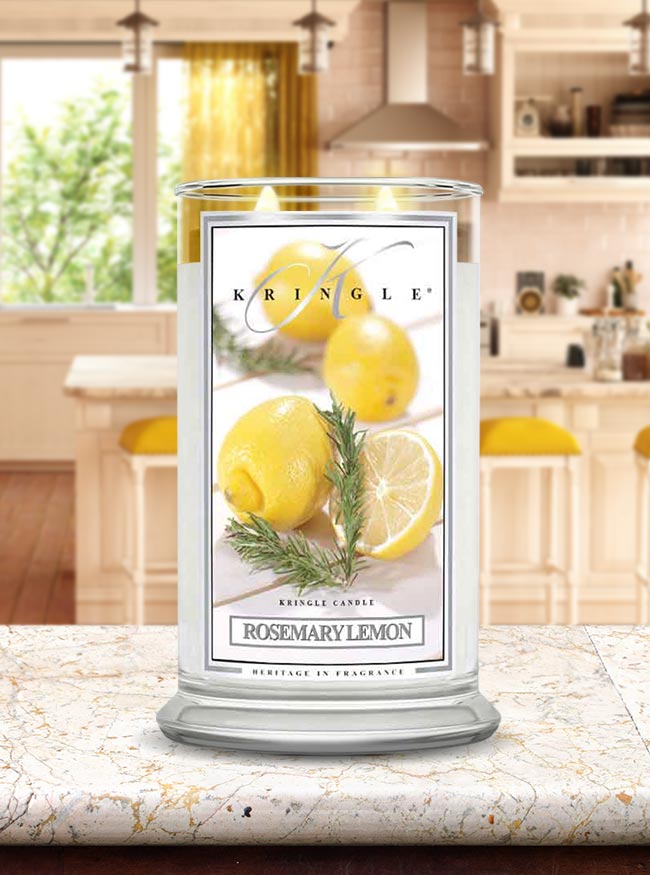 Photo of a lit Rosemary Lemon glass candle jar with a label showing sliced lemons and a sprig of rosemary.